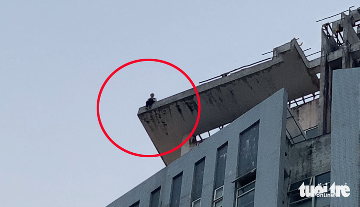 Cô gái ngồi cheo leo trên tầng thượng của tòa tháp 27 tầng ở TP Vinh chiều 7-12 - Ảnh: DOÃN HÒA