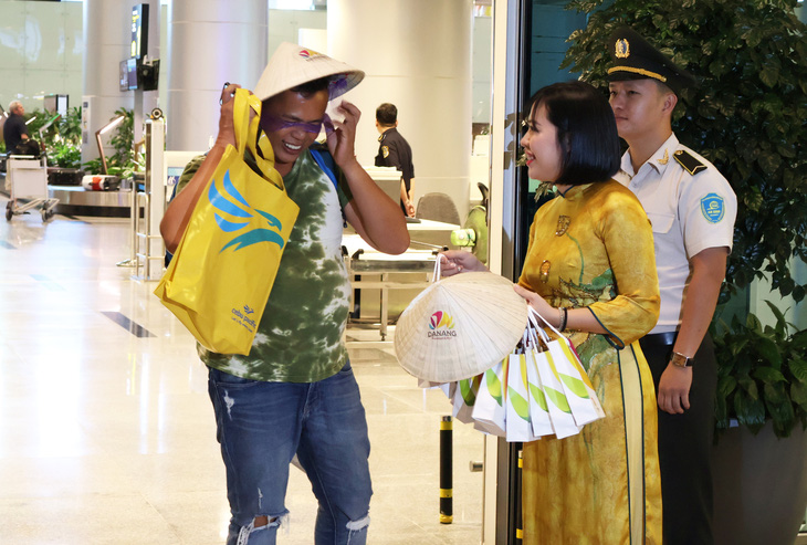 Hành khách Philippines xuống sân bay được tặng chiếc nón và quà - Ảnh: LÊ TRUNG