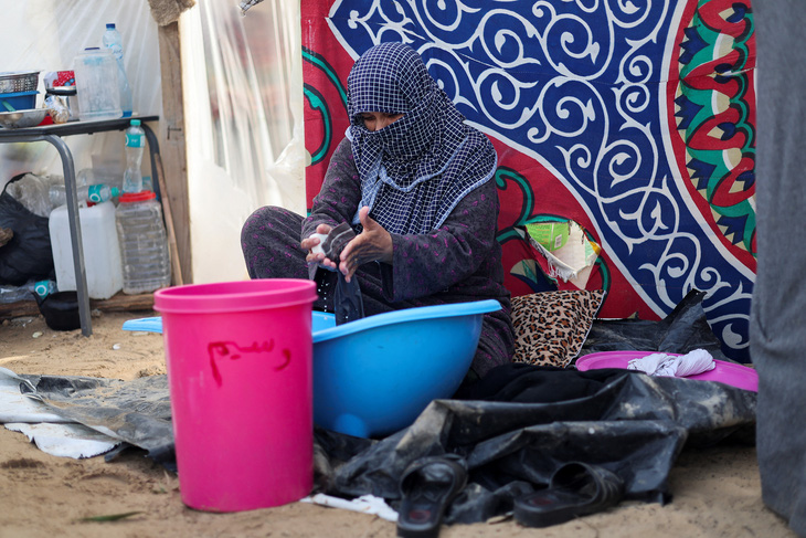Phụ nữ Palestine giặt quần áo trong lều tạm giữa lúc di tản vì chiến sự, phía nam Dải Gaza, ngày 8-12 - Ảnh: REUTERS