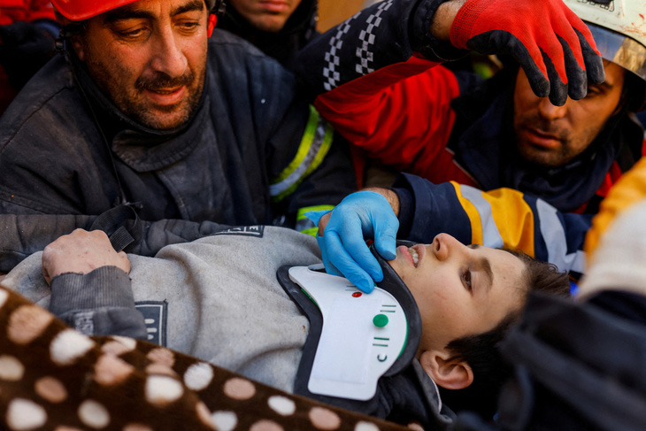 Lực lượng cứu hộ hỗ trợ bé trai Mohammad Alkanaas, 11 tuổi sống sót sau trận động đất ở Hatay, Thổ Nhĩ Kỳ ngày 11-2-2023 - Ảnh: REUTERS