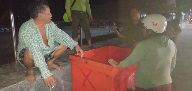 Anh Phương - ngư dân Côn Đảo, người mặc áo ca rô - bên thùng nước đá giúp anh thoát nạn - Ảnh: BÙI QUANG KHẢI