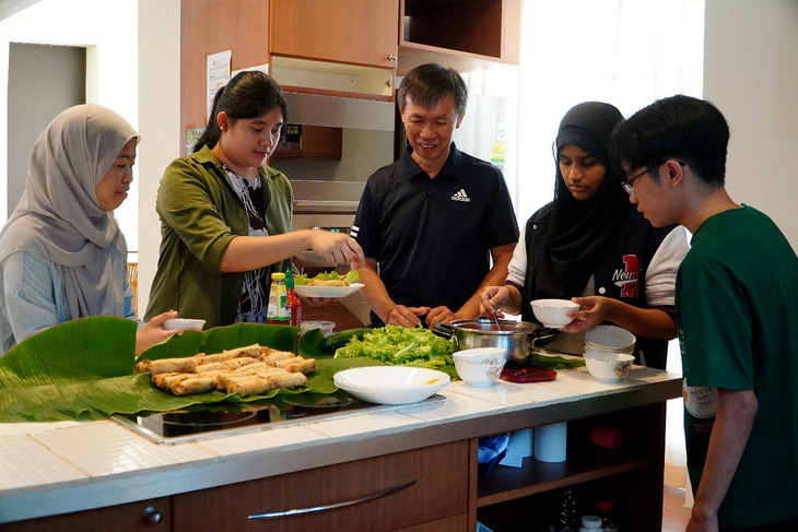 Thầy Nghĩa (giữa) vừa dạy sinh viên Brunei nấu các món truyền thống của Việt Nam vừa dạy các em tiếng Việt - Ảnh: NVCC