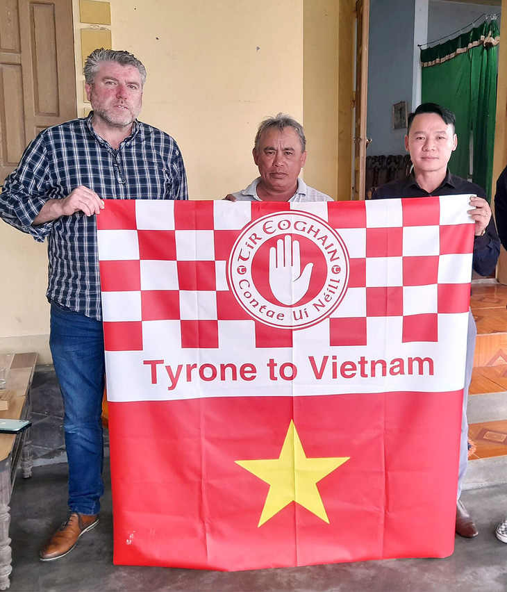 Tài xế John Hurson và lá cờ ông mang đến để sẻ chia với một gia đình ở Nghệ An, thân nhân của một trong 39 người di cư - Ảnh: NVCC