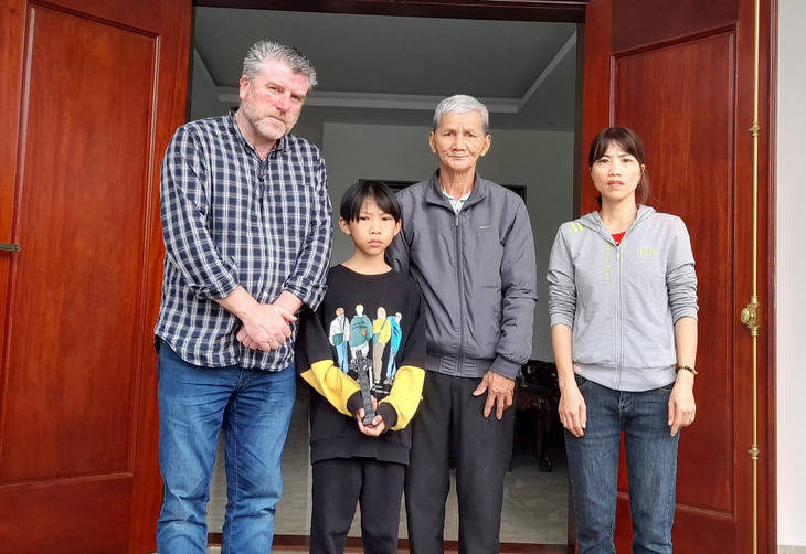 Tài xế John Hurson chụp ảnh cùng một gia đình ở Nghệ An, thân nhân của một trong 39 người di cư - Ảnh: NVCC