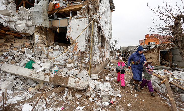Một người mẹ dẫn hai con rời khỏi khu nhà bị tên lửa đánh sập ở ngoại ô Kiev, Ukraine ngày 26-1-2023 - Ảnh: Reuters