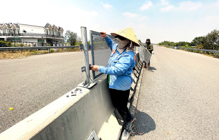 Công nhân tháo những tấm chống lóa trên công trình đường cao tốc Bến Lức - Long Thành nhằm chống mất cắp - Ảnh: LÊ PHAN