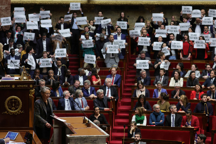 Các thành viên cánh tả của Quốc hội giơ biểu ngữ phản đối và hát quốc ca ngăn Thủ tướng Pháp Elisabeth Borne phát biểu về cải cách hưu trí tại Quốc hội Pháp, ngày 16-3-2023. - Ảnh: REUTERS