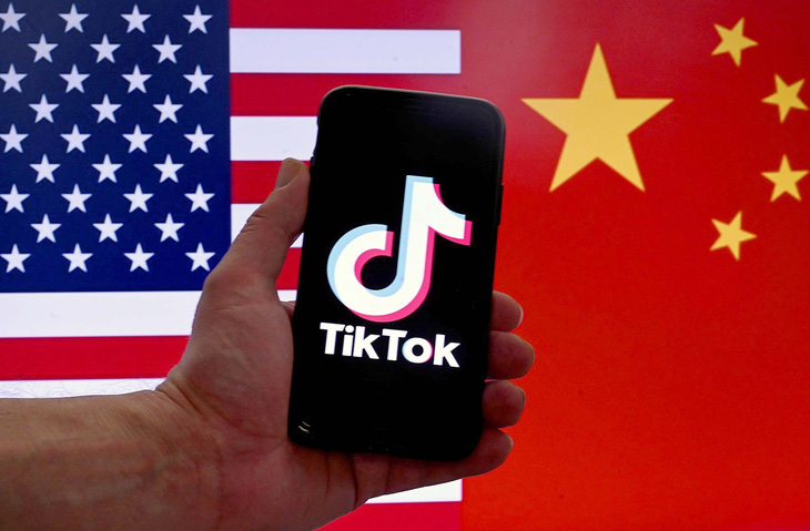Ảnh minh họa của Hãng tin AFP cho thấy logo của TikTok hiển thị trên màn hình điện thoại iPhone phía trước cờ Mỹ và Trung Quốc - Ảnh: AFP