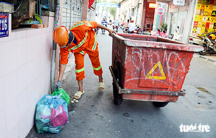 Nhân viên thu gom rác tại hẻm 391 Trần Hưng Đạo, quận 1, TP.HCM - Ảnh: PHƯƠNG QUYÊN