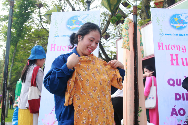 Chị Nguyễn Thị Thanh Trúc (công nhân của Công ty môi trường và Công trình đô thị Thừa Thiên Huế) bên tà áo dài mình vừa chọn được tại Ngày hội Hương Sắc Huế - Ảnh: NHẬT LINH