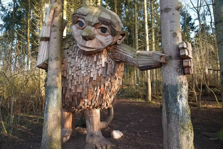 Trong hình là một tác phẩm của điêu khắc gia nổi tiếng người Đan Mạch Thomas Dambo, người chuyên sáng tạo từ vật liệu tái chế. Bức tượng làm từ gỗ tái chế này được đặt tại TP Vallensbaek, Đan Mạch. Hình chụp ngày 23-3 - Ảnh: AFP