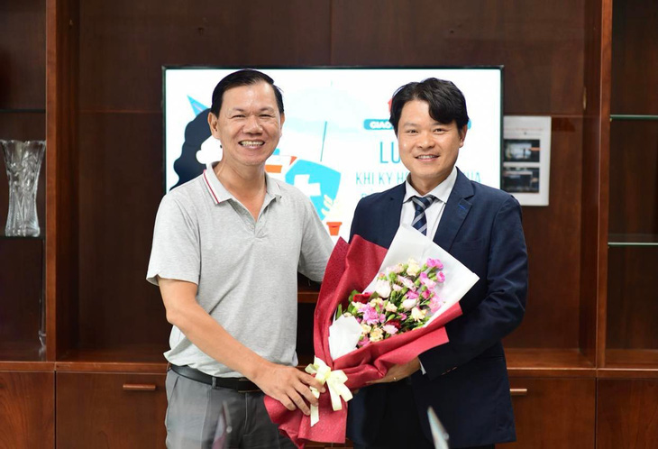 Phó tổng thư ký tòa soạn Báo Tuổi Trẻ Nguyễn Trường Uy (trái) tặng hoa cho luật sư Trần Minh Hải - Ảnh: QUANG ĐỊNH