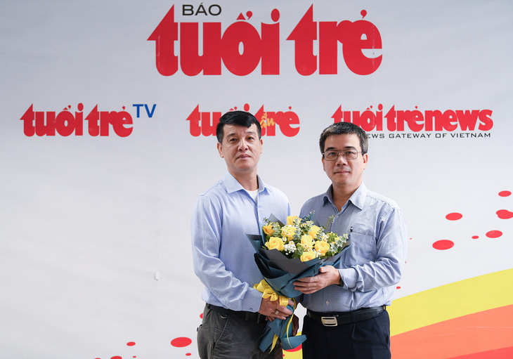 Đại diện Báo Tuổi Trẻ Văn phòng Hà Nội (trái) tặng hoa cho ông Ngô Trung Dũng - phó tổng thư ký Hiệp hội Bảo hiểm Việt Nam - Ảnh: NAM TRẦN