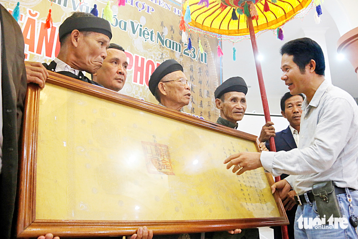 Ông Nguyễn Hữu Hoàng (bìa phải) trao tặng lại các đạo sắc phong quý do vua Duy Tân ban tặng từng bị mất cắp cho làng Quý Lộc (huyện Phú Lộc, Thừa Thiên Huế) vào năm 2018 - Ảnh: NHẬT LINH