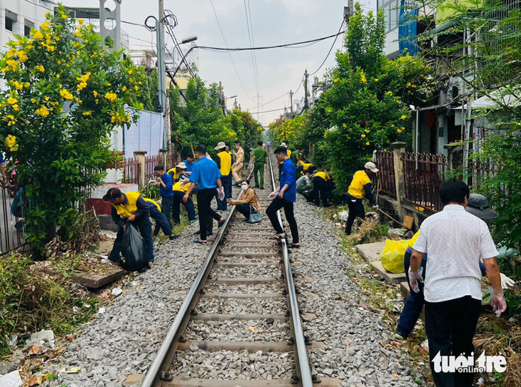 Nhân viên Công ty cổ phần Đường sắt Sài Gòn cùng các đoàn viên thanh niên thu dọn rác và xà bần - Ảnh: XUÂN PHÚC