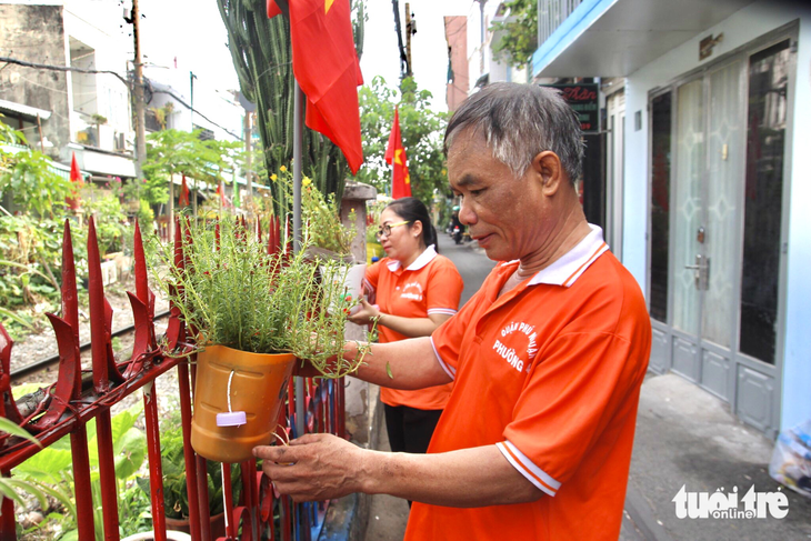 Mô hình trồng những chậu hoa tái chế dọc hàng rào đường sắt nhằm hạn chế người dân treo rác và phơi đồ làm mất mỹ quan khu phố - Ảnh: LƯU DUYÊN