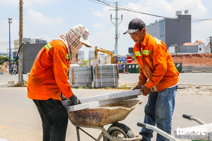 Các công nhân làm việc trên đường Lương Định Của, TP Thủ Đức vất vả dưới thời tiết nắng nóng trưa 23-4 - Ảnh: PH.QUYÊN