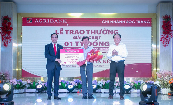 Đại diện lãnh đạo Agribank, Phó Tổng giám đốc Lê Hồng Phúc trao 1 tỉ đồng cho khách hàng trúng giải đặc biệt - Ảnh: AGR