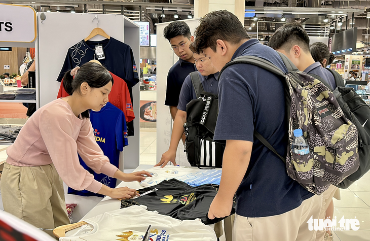 Một nhóm sinh viên Campuchia hỏi mua áo lưu niệm SEA Games 32 - Ảnh: N.K