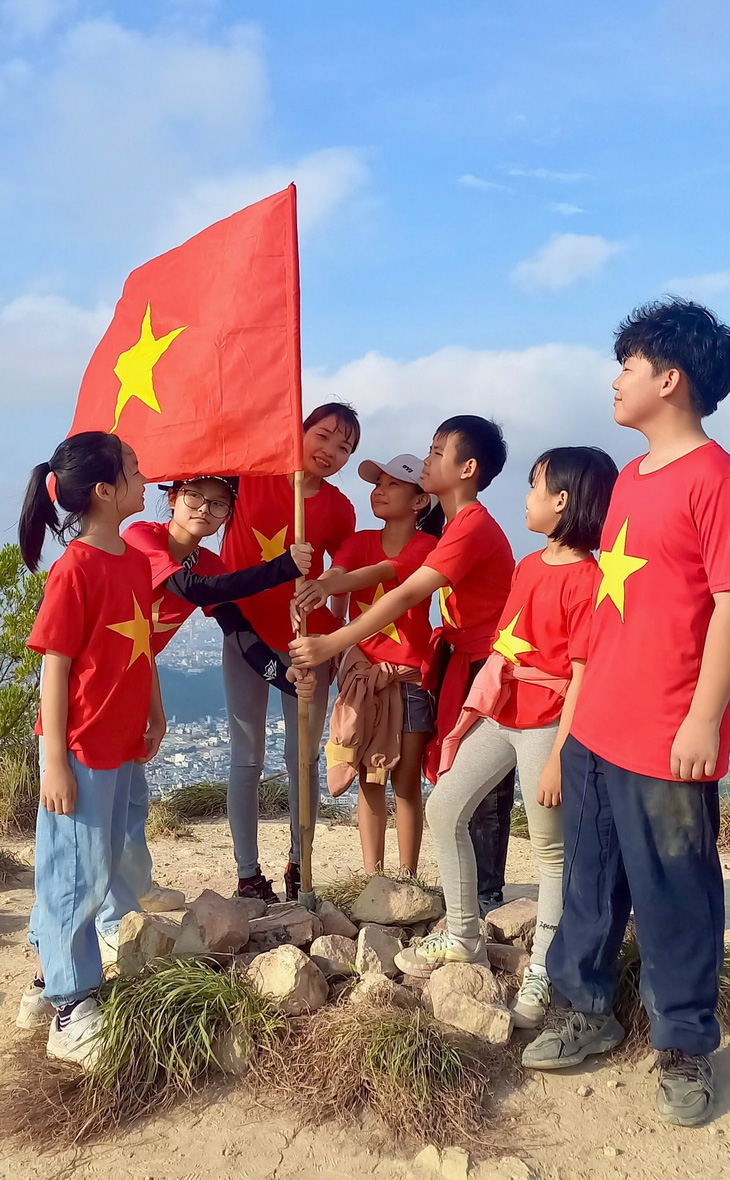 Các em học sinh và phụ huynh cắm cờ trên đỉnh Cô Tiên - Ảnh: THỤC NGHI