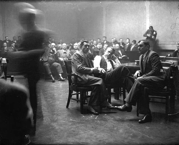 Tên cướp ngân hàng khét tiếng John Dillinger (áo trắng) bị còng tay vào cảnh sát trong phiên tòa xét xử vào tháng 2-1934 - Ảnh: Chicago Tribune