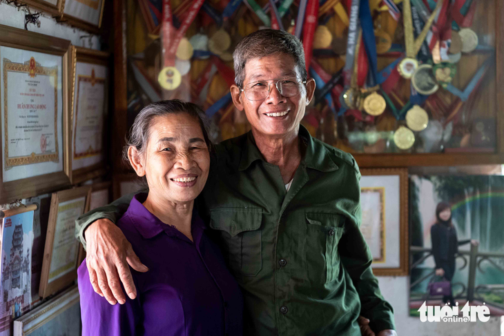 Cha mẹ Nguyễn Thị Oanh và bộ sưu tập huy chương đồ sộ của con gái giành được trong nhiều năm thi đấu - Ảnh: NGUYỄN KHÁNH