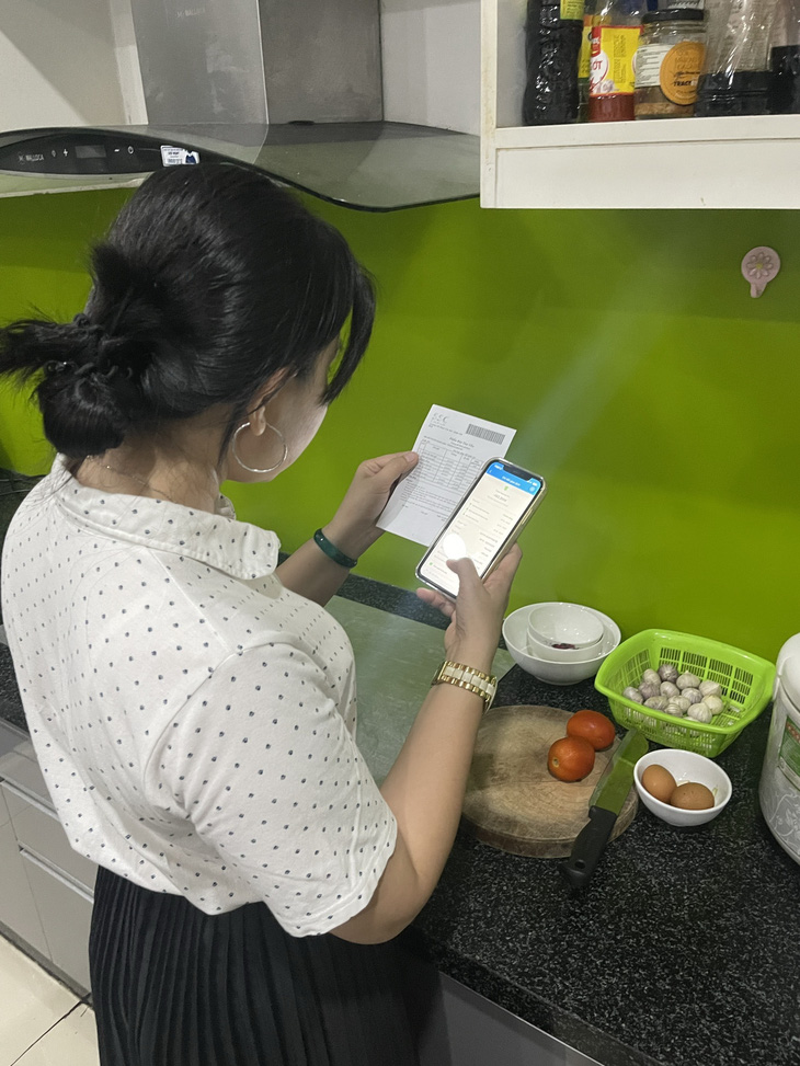 Chị Trần Kim Phụng vừa làm bếp vừa thanh toán học phí cho con học tại Trường THPT Bình Tân