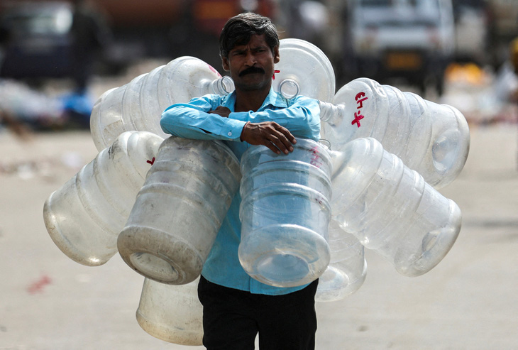 Người đàn ông quấn quanh cổ nhiều bình rỗng để châm nước và sau đó bán cho người dùng ở thủ đô New Delhi, Ấn Độ ngày 18-5 - Ảnh: REUTERS