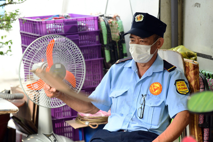 Ông Lê Văn Chính, bảo vệ một cửa hàng tại quận Bình Thạnh, TP.HCM, phải lấy bìa giấy quạt tay cho đỡ nóng vì bị mất điện tạm thời (ảnh chụp lúc 16h50 ngày 19-5) - Ảnh: QUANG ĐỊNH