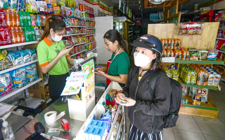 Một cửa hàng trên đường Nguyễn Văn Đậu, quận Bình Thạnh, TP.HCM phải tính tiền khách hàng bằng điện thoại do bị mất điện tạm thời lúc 16h45 ngày 19-5 - Ảnh: QUANG ĐỊNH