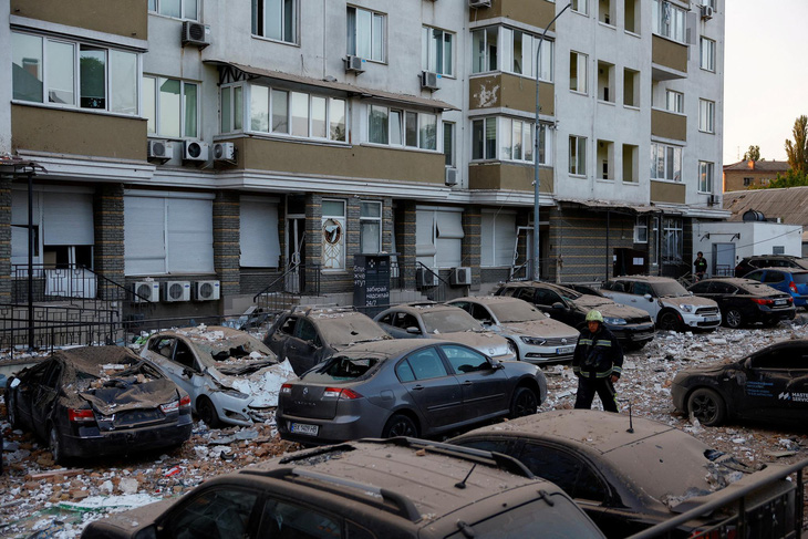 Lính cứu hỏa xuất hiện bên cạnh những chiếc ô tô bị hư hại sau cuộc không kích quy mô lớn của Nga ở thủ đô Kiev (Ukraine) ngày 30-5 - Ảnh: REUTERS