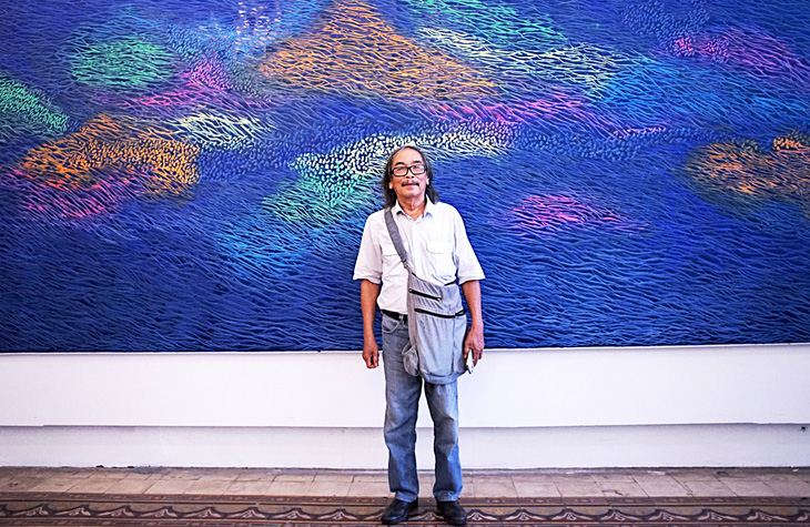 Họa sĩ Đỗ Chung trước tác phẩm sơn dầu khổ lớn tại triển lãm “Người đàn bà trên sông Hằng” - Ảnh: H.VY