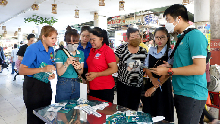 Các bạn trẻ tư vấn cho tiểu thương, bà con sử dụng thanh toán không tiền mặt tại chợ Nguyễn Tri Phương sau lễ ra quân hè tình nguyện quận 10 (TP.HCM) ngày 10-6 - Ảnh: K.ANH