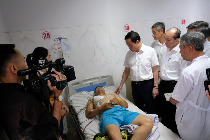 Phó thủ tướng Trần Lưu Quang động viên đại úy Lê Kiên Cường (35 tuổi), cán bộ Công an xã Ea Ktur - nạn nhân bị thương trong vụ hai trụ sở UBND xã bị tấn công - Ảnh: MAI VINH