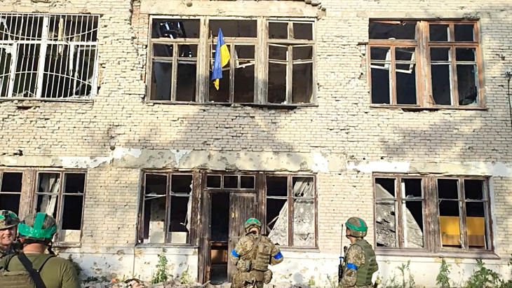 Binh sĩ Ukraine đứng trước tòa nhà treo cờ Ukraine tại địa điểm được cho là làng Blahodatne ở vùng Donetsk, miền đông Ukraine hôm 11-6 - Ảnh: Reuters