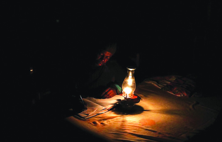 Một người phải làm việc với đèn dầu trong đợt cúp điện định kỳ ở Nam Phi. Ảnh: Reuters