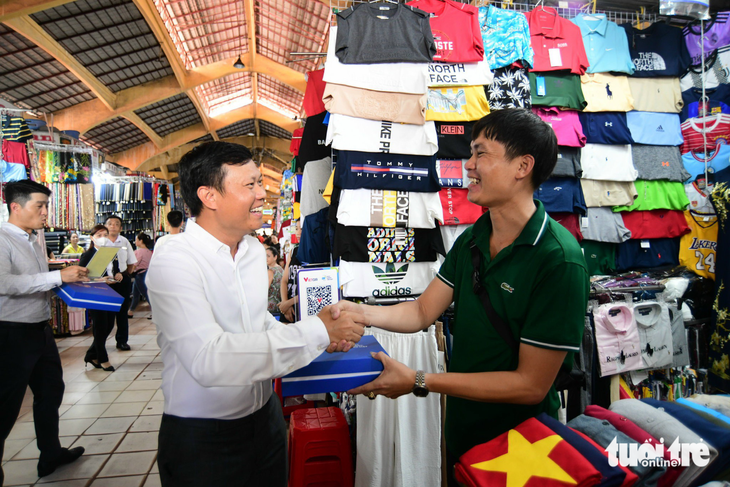 Ông Nguyễn Đức Huỳnh – Trưởng đại diện tại TP.HCM của Công ty cổ phần Thanh toán quốc gia Việt Nam NAPAS - trao mã QR thanh toán không tiền mặt cho tiểu thương - Ảnh: QUANG ĐỊNH