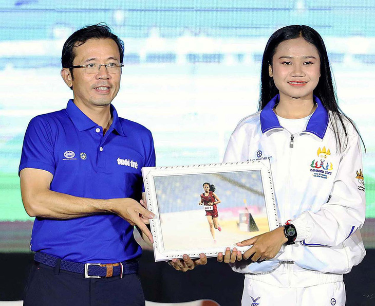Phó tổng biên tập báo Tuổi Trẻ Trần Xuân Toàn trao tấm hình Bou Samnang chạy dưới mưa ở SEA Games 32 để làm kỷ niệm tại buổi giao lưu - Ảnh: N.K.