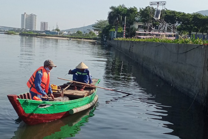 Công nhân môi trường dọn rác dưới sông Hàn ở khu vực khán đài bắn pháo hoa - Ảnh: T. TRUNG