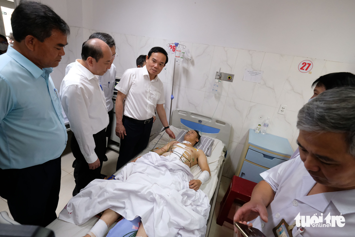 Phó thủ tướng Trần Lưu Quang động viên thượng úy Đàm Đình Bốp (30 tuổi), phó trưởng Công an xã Ea Ktur - nạn nhân trong vụ hai trụ sở UBND xã bị tấn công vào ngày 11-6, tại Bệnh viện Đa khoa vùng Tây Nguyên - Ảnh: MAI VINH