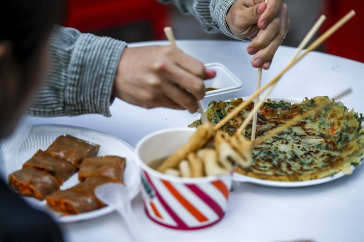 Du khách thử món bánh kếp hành hải sản và chả cá trong nước dùng cá mòi tại một lễ hội ẩm thực khu vực được tổ chức ở Quận Mapo của Seoul năm 2022 - Ảnh: Korea Times