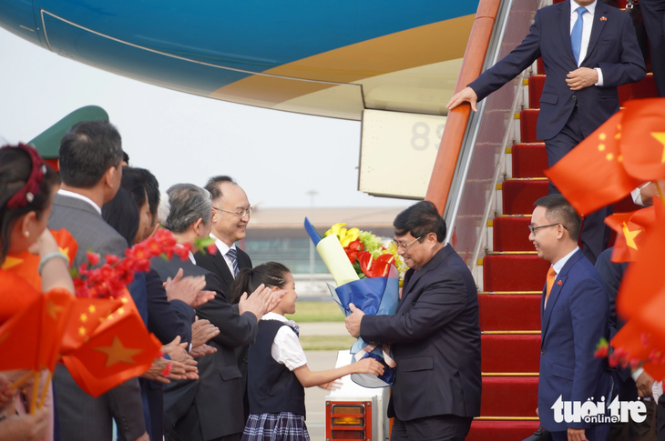 Thủ tướng nhận hoa từ một em bé Trung Quốc - Ảnh: NGỌC AN