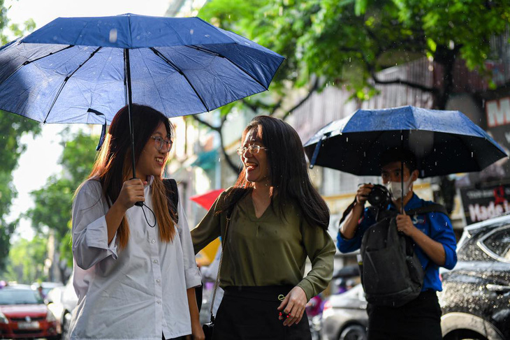 Thí sinh có mặt tại điểm thi trường THPT Chu Văn An, Tây Hồ, Hà Nội. Do trời mưa, thí sinh được các tình nguyện viên hỗ trợ vào khu vực thi - Ảnh: NAM TRẦN