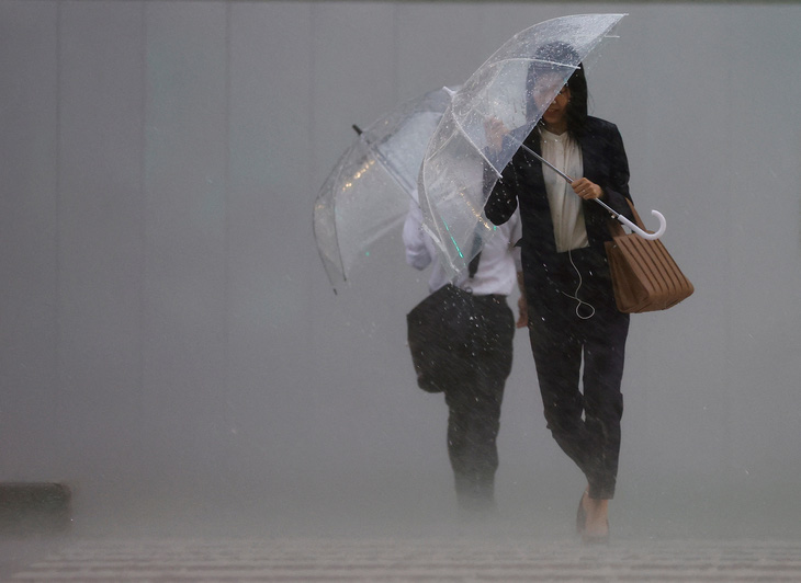 Áp thấp nhiệt đới từ siêu bão Mawar gây mưa lớn ở Nhật Bản hôm 2-6, khiến hơn 300 chuyến bay bị hủy, giao thông công cộng gián đoạn, nhiều nơi ngập lụt. Trong ảnh, người dân mang ô trong cơn mưa nặng hạt ở Tokyo - Ảnh: REUTERS