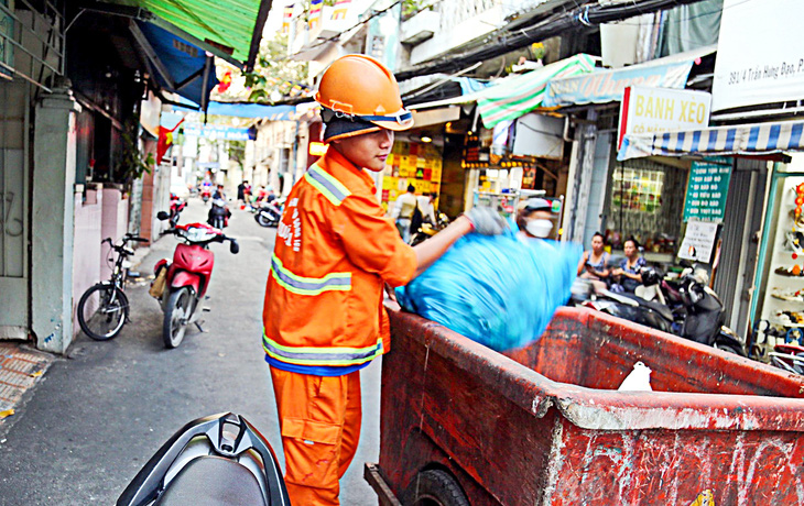 Nhân viên thu gom rác tại hẻm 391 Trần Hưng Đạo, quận 1, TP.HCM - Ảnh: PHƯƠNG QUYÊN