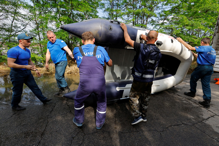 Các thành viên của Bộ tình trạng khẩn cấp của Nga mang theo một chiếc thuyền bơm hơi trong chiến dịch cứu hộ sau vụ vỡ đập Nova Kakhovka ngày 7-6 - Ảnh: REUTERS