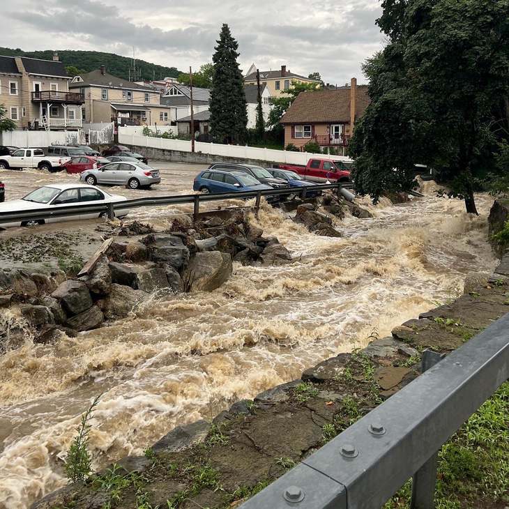 Nước mưa chảy cuồn cuộn quanh bãi đậu xe ở Highland Falls, New York, Mỹ ngày 9-7 - Ảnh: REUTERS