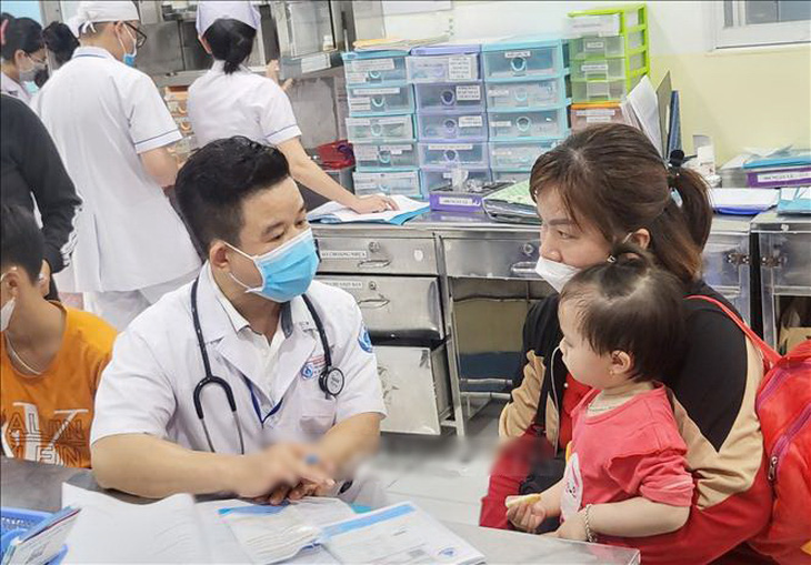 Bác sĩ Dư Tấn Quy, trưởng khoa nhiễm - thần kinh, Bệnh viện Nhi đồng 1,  khám cho trẻ mắc tay chân miệng - Ảnh: TTXVN