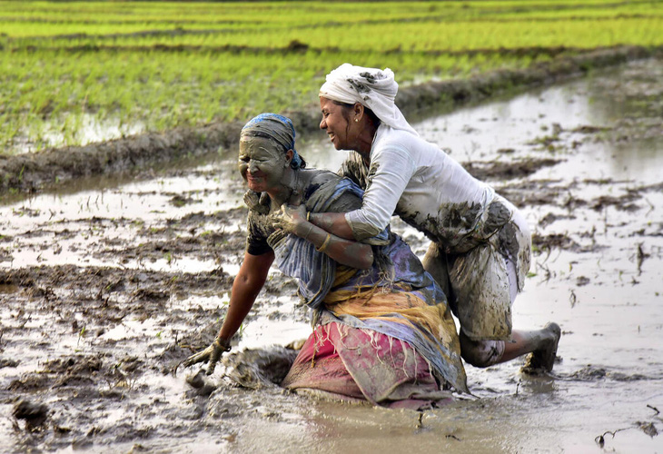 Hai người phụ nữ đùa vui với bùn sau khi cấy xong trên cánh đồng ở làng Uttarpara, huyện Baksa, bang Assam miền đông bắc Ấn Độ - Ảnh: DECCAN HERALD