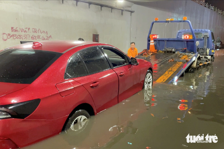 Xe cứu hộ &quot;giải cứu&quot; một ô tô giữa dòng nước ngập ở hầm chui Tân Phong - Ảnh: AN BÌNH